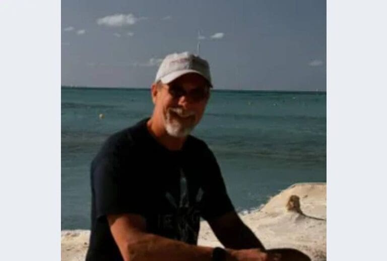 A man sitting on the beach with his bike.