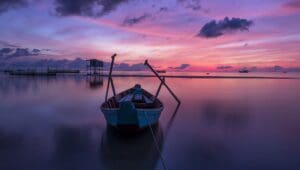 A boat floating on top of water at sunset.