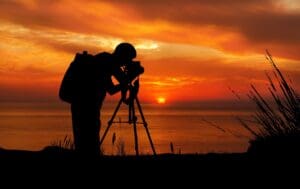 A person standing in front of the ocean with a camera.